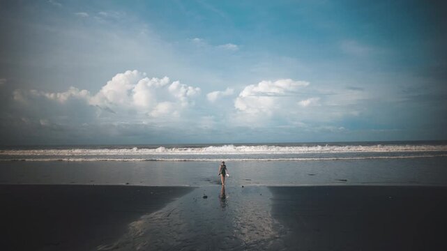 Relaxed Woman Standing on Wide Tropical Beach Under Dramatic Clouds