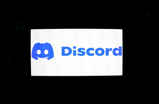 Discord Logo and Wordmark on a Bright White Smartphone Screen Over a Dark Keyboard, Representing Social Communication, Online Communities, Instant Messaging, and Digital Gaming Culture.