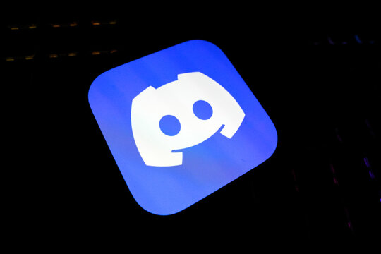 Discord Logo in White on a Bright Blue Square App Icon, Displayed on a Screen Over a Dark, Textured Keyboard Background, Symbolizing Social Media, Online Communities, and Digital Communication.
