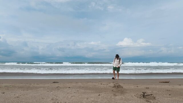 Man Kicking Coconut on Tropical Beach Under Dramatic Cloudy Sky