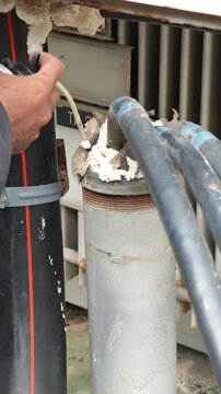 Utility worker injecting expanding foam to seal hole during underground cable repair.