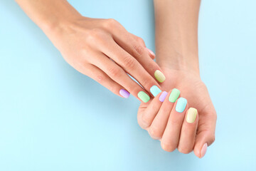 Fototapeta premium Woman showing her stylish colorful manicure on light blue background, closeup
