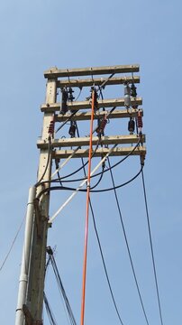 Utility lineman using hot stick to open drop out fuse on distribution power pole.