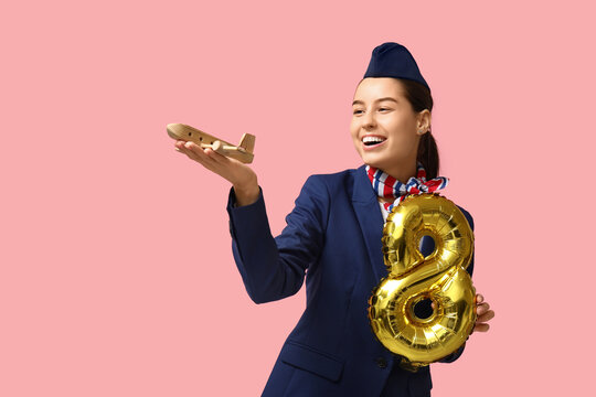 Young stewardess with balloon in shape of figure 8 and toy plane on pink background. Women's Day celebration