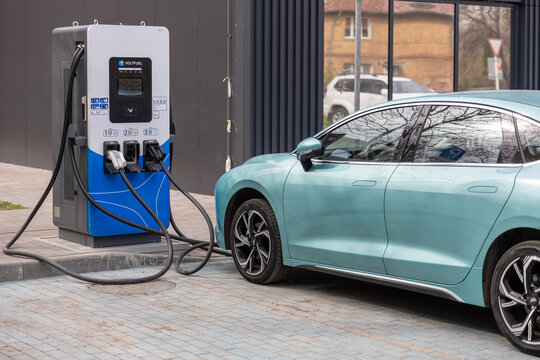 Modern AmberAuto electric car charging at public EV station near urban street with charger infrastructure. Kaliningrad, Russia, April 14, 2026