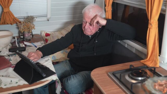 Senior man using digital tablet inside cozy caravan van life digital nomad