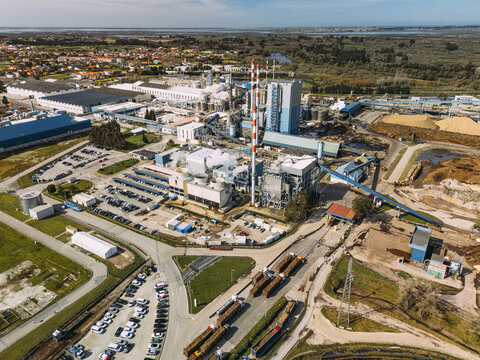 Aerial view of a vast industrial complex with towering chimneys piercing the sky, contrasting against the surrounding greenery, Cacia, Aveiro District, Portugal.