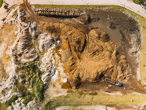 Aerial view of vast, sculpted mounds of contrasting light sand and rich, earthy wood chips dominating an industrial landscape, Cacia, Aveiro District, Portugal.