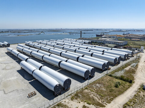 Aerial view of rows of cylindrical white structures contrasting against the gray concrete, with the blue water in the background, Aveiro, Aveiro, Portugal.
