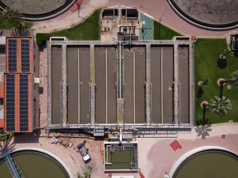 Overhead view of rectangular aeration basins at a wastewater treatment facility showing activated sludge process with parallel treatment lanes, diffuser piping, solar panels, and circular clarifiers