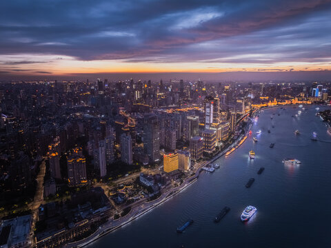 Aerial view of the illuminated Pudong skyline and boats on the Huangpu River at twilight, with city lights reflecting on the dark water, Pu Dong Xin Qu, Shang Hai Shi, China.