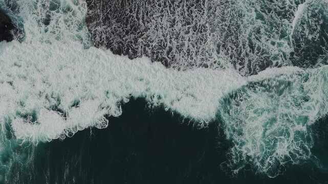 Aerial view of crashing ocean waves and white sea foam at Mesra Beach in Kecamatan Tanjungsari, Daerah Istimewa Yogya, Indonesia.