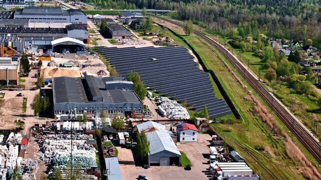 Aerial drone footage reveals large solar panel farm alongside industrial warehouses, storage yards and railway tracks in Jelgava, Latvia