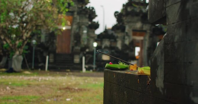 Burning incense stick on stone wall at traditional Balinese Hindu temple Bali