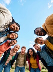 Obraz premium Diverse group of friends smiling, looking down at camera, against blue sky