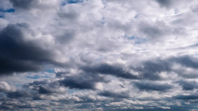 Timelapse displays the dynamic movement of heavy dark storm formations dominating the sky. The ominous weather hints at a dramatic storm while patches of blue peek through the cover.