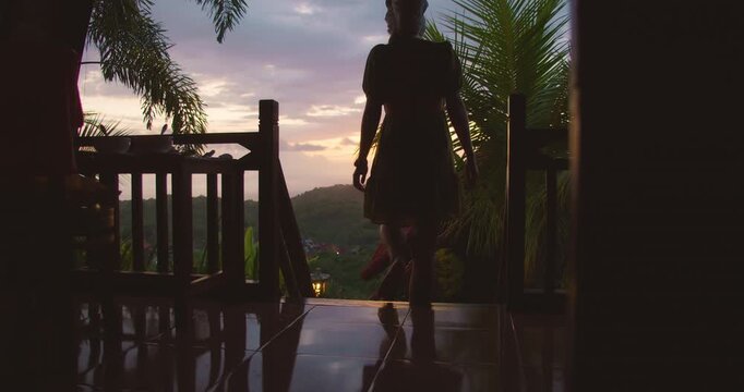 Silhouette of a woman sitting on a balcony floor during a vibrant dusk in Nusa Penida