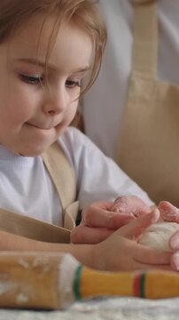 Young child learning to bake with adult guidance, shaping dough and rolling pastry together in a warm home kitchen, highlighting shared family cooking moments