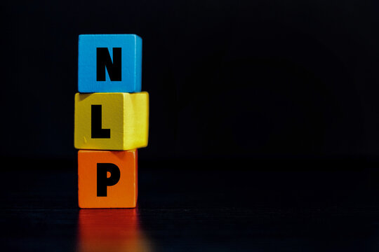 Colorful wooden blocks with "NLP" text against a dark background. Representing Neuro-Linguistic Programming, communication excellence, and cognitive behavioral psychology concepts