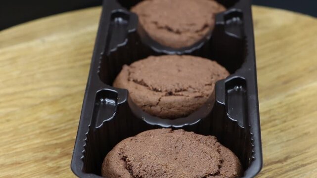 Rotating close-up of chocolate cookies in a packaging tray, highlighting their texture.