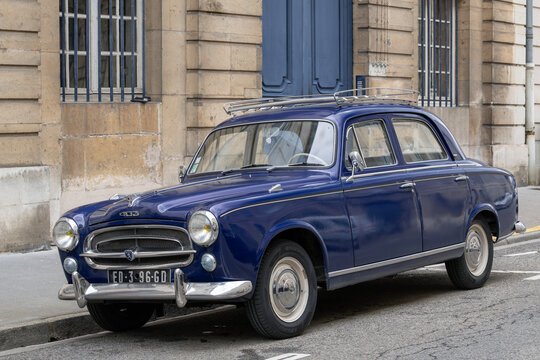 Nancy, France - April 9th 2022 : View on a blue Peugeot 403 parked on a street with the facade of an old building in the background.