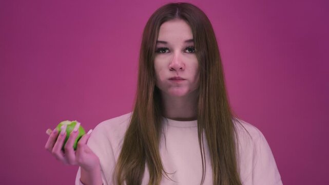 Teen girl eats a green apple. Teenager female bites an apple. Young woman holds an apple in hand. Healthy lifestyle and diet. Organic meal, Lunch Snack. Crisp fruit, nutrition and wellness
