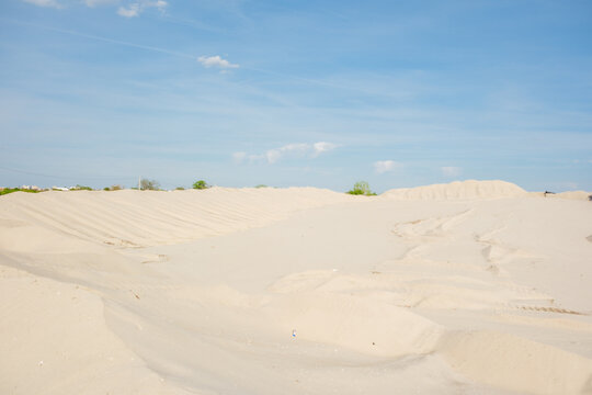 View of large sand dunes and piles with tire tracks under a clear blue sky in a quarry Futog, Vojvodina, Serbia.