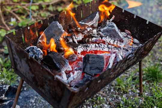 Hot burning charcoal and bright orange flames in metal grill brazier for outdoor barbecue.