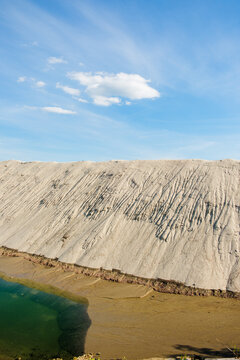 View of a large sand quarry with eroded slopes and a green pond under a clear blue sky in Futog, Vojvodina, Serbia.