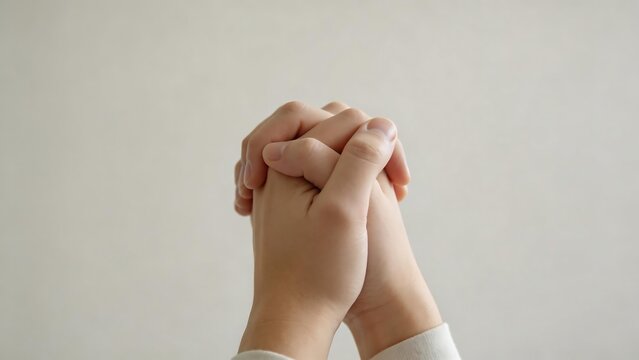 Hands clasped together in front of a plain wall