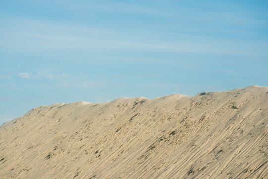 View of large sand dunes with textured slopes under a clear blue sky in Futog, Vojvodina, Serbia.