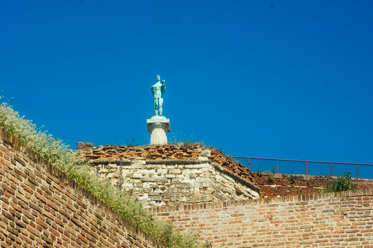 View of the Pobednik monument standing atop the historic brick walls of the Kalemegdan Fortress under a clear blue sky in Beograd, Grad Beograd, Serbia.