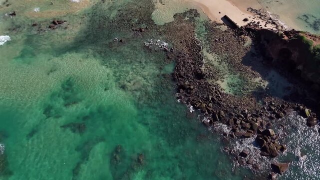 Aerial close-up of water and the rocky shore of Parrot Rock island. Mirissa, Sri Lanka