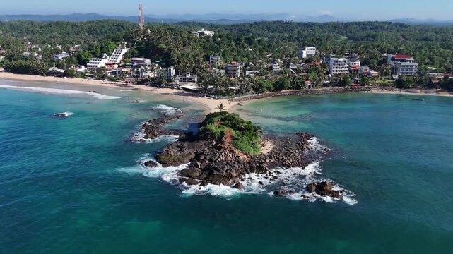 Drone shot of the coastline featuring the Parrot Rock landmark and village buildings. Mirissa, Sri Lanka