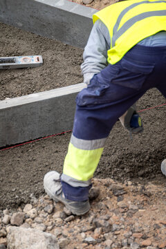 Construction worker leveling ground for a new sidewalk The Concept of manual labor