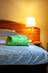 Zielone ręczniki na łóżku w pokoju hotelowym © Freshfanpage