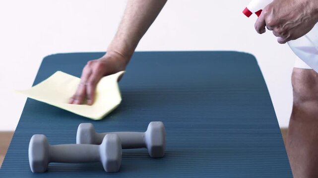 Close up of hands a business owner sanitizing the workbenches in their gym.Bacteria can spread so easily