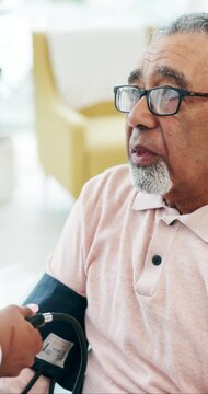 Old man, blood pressure test and talk at clinic with nurse, equipment or wellness check in retirement. Elderly patient, medical professional and monitor with assessment, discussion or healthcare exam