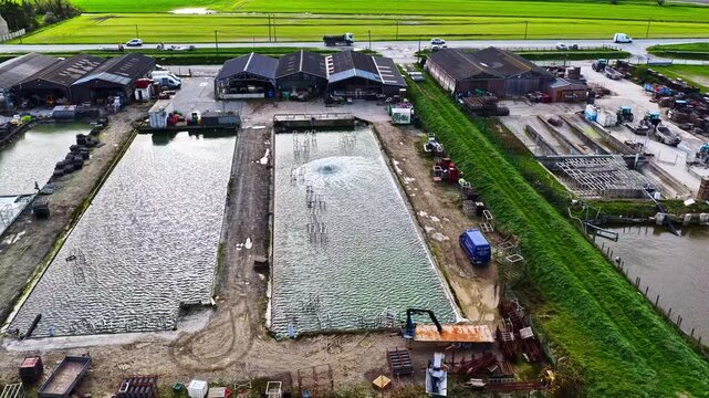 Aerial view of fish farm ponds with buildings and equipment in rural fields