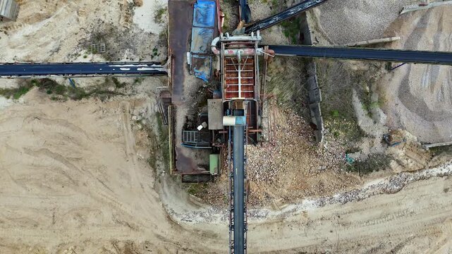 Top-down aerial view of a mobile aggregate processing plant in a sand and gravel quarry, featuring industrial conveyor belts, sorting machinery, stockpiles of material, and heavy equipment on site.