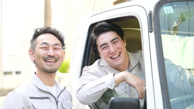 作業員のチームワークや配送業や輸送の転職や採用、求人などのカメラ目線笑顔　トラックの窓から笑顔の仲良しドライバーの動画