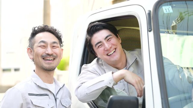 【スローモーション】作業員のチームワークや配送業や輸送の転職や採用、求人などのカメラ目線笑顔　トラックの窓から笑顔の仲良しドライバーの動画　