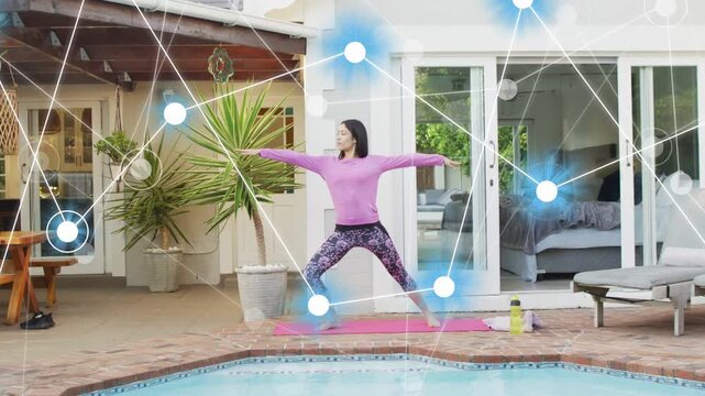 Woman holding Warrior II on pink mat by pool as blue nodes appearing, guiding fitness alignment