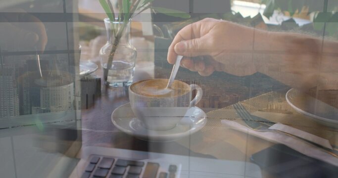 Stirring hand swirling spoon in cup on saucer at cafe, with laptop, vase, napkin, skyline overlay