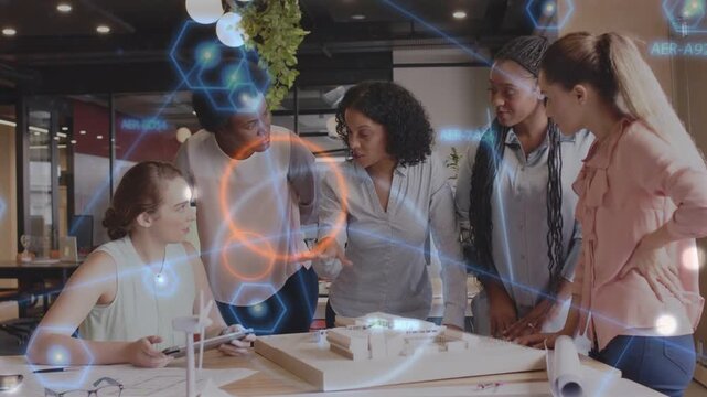 Lead gesturing and activating overlay marking design model while five women reviewing tablet plans