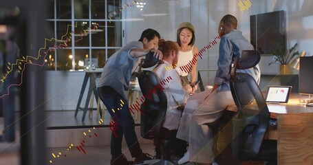 Fototapeta premium Meeting team in business casual reviewing market charts at night in office with laptop, smartphone