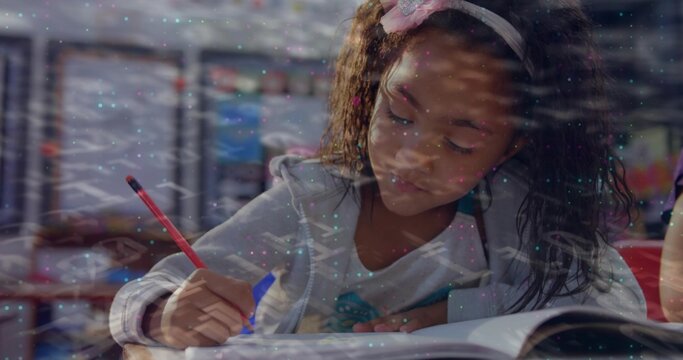 Writing student leaning at school desk, holding red pencil and open notebook, wearing zip-up hoodie