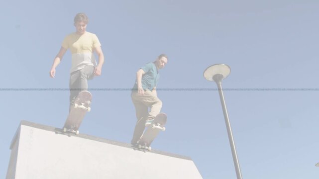 Two skateboarders shifting weight and dropping into concrete ramp, practicing sports run past lamp