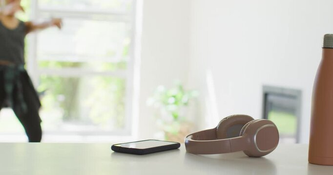 African American woman entering room, dancing toward counter with phone headset bottle, copy space