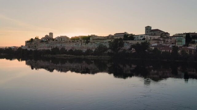 Scenic sunset over the Douro river with Zamora's historic skyline and cathedral reflecting in the water, Spain